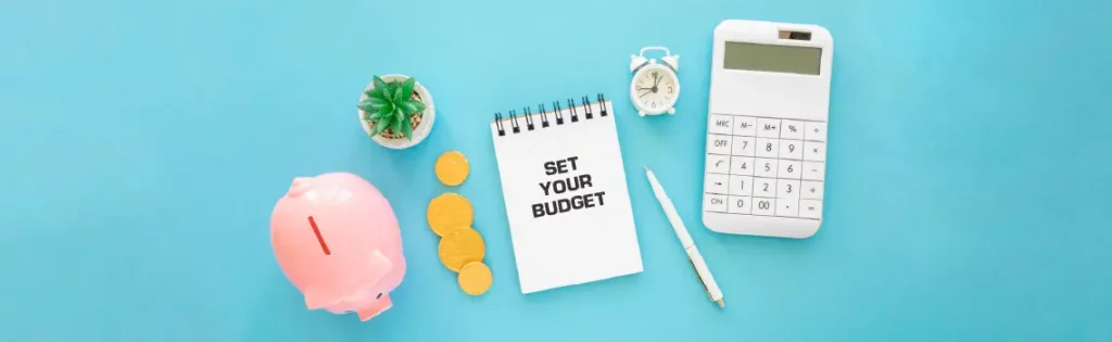 Budget planning essentials with piggy bank, coins, calculator, and notebook on a blue background.