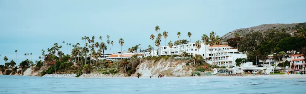 Scenic view of Malibu coastline with beachfront homes, palm trees, and cliffs, showcasing a desirable area for jumbo mortgages in California